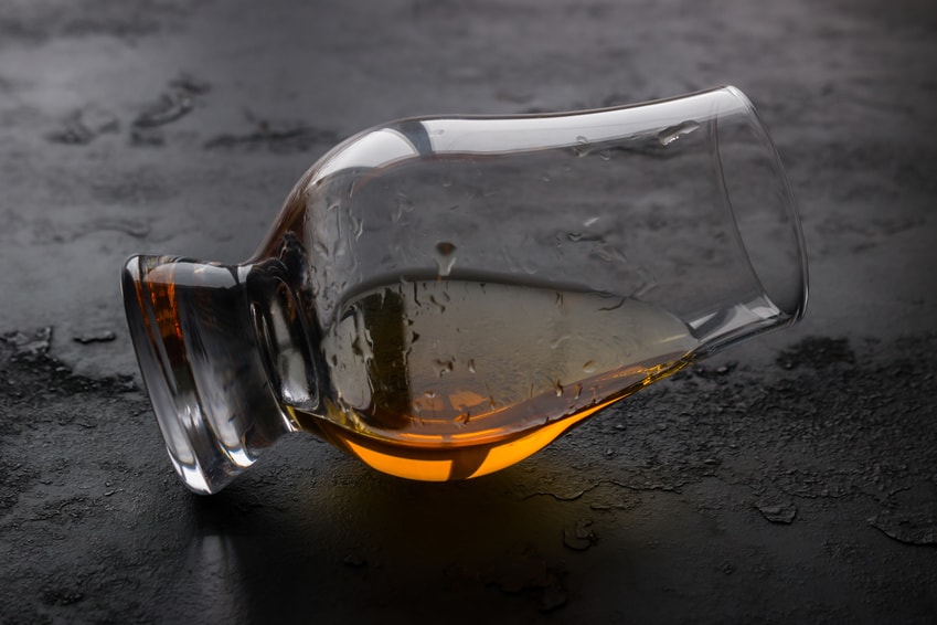 A glencairn on it's side with some bourbon in